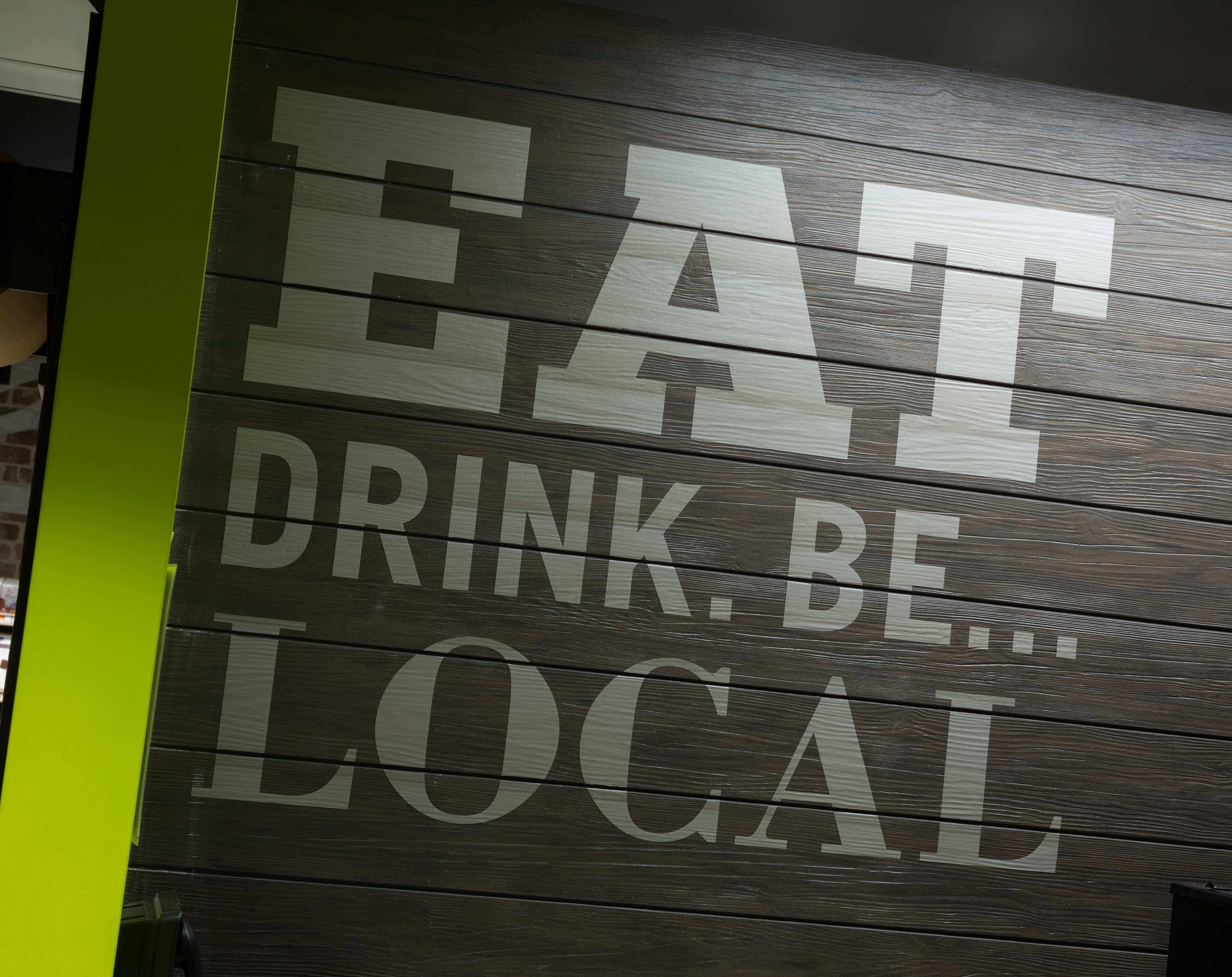 "Eat Drink. Be... Local" experiential graphics on a wood panel wall in Brothers Marketplace Medfield, MA