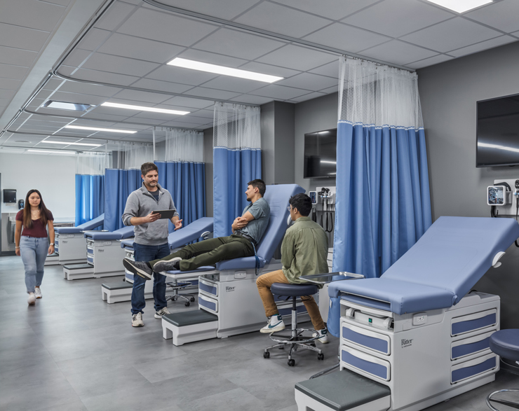 Students take a class in a new classroom with hospital beds 