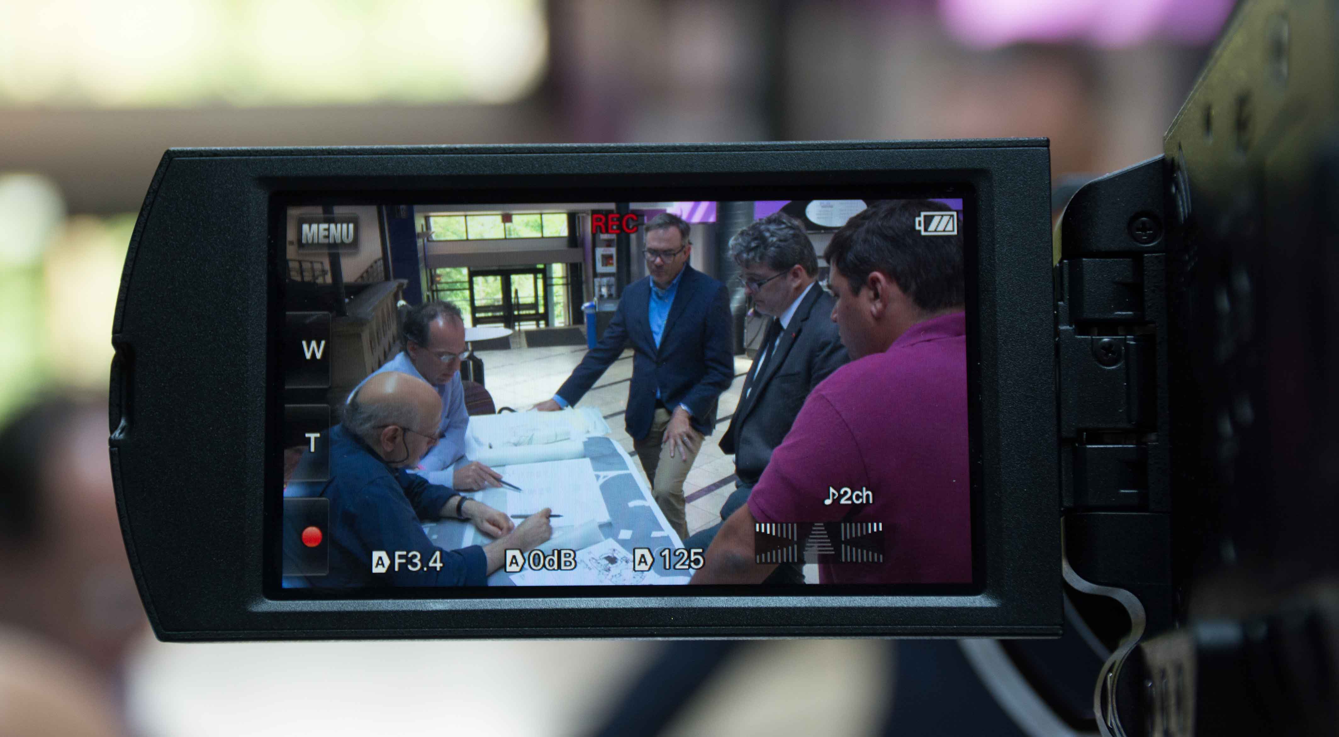 Through a camera lens, people are seen working together