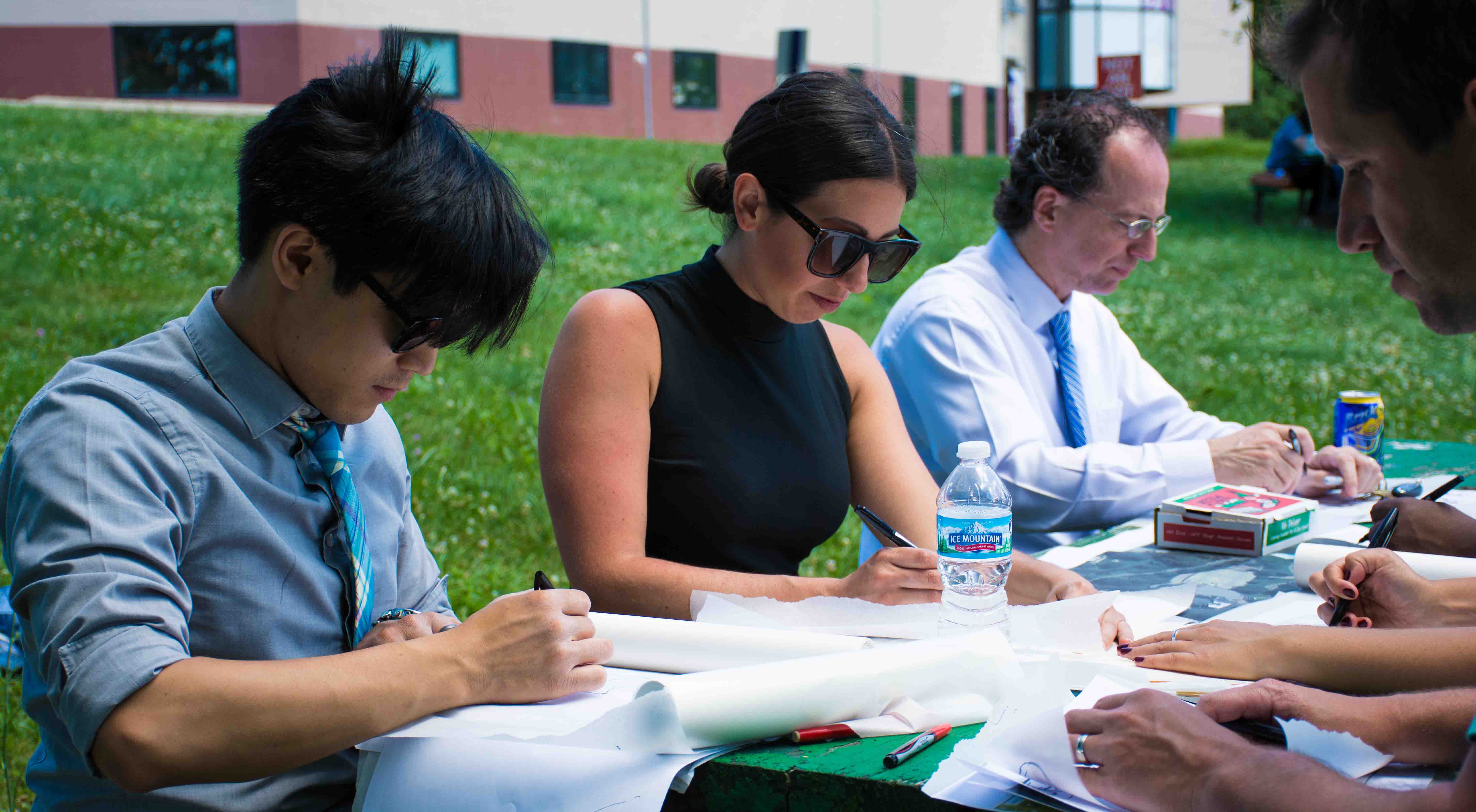 Four people sketch at a picnic table