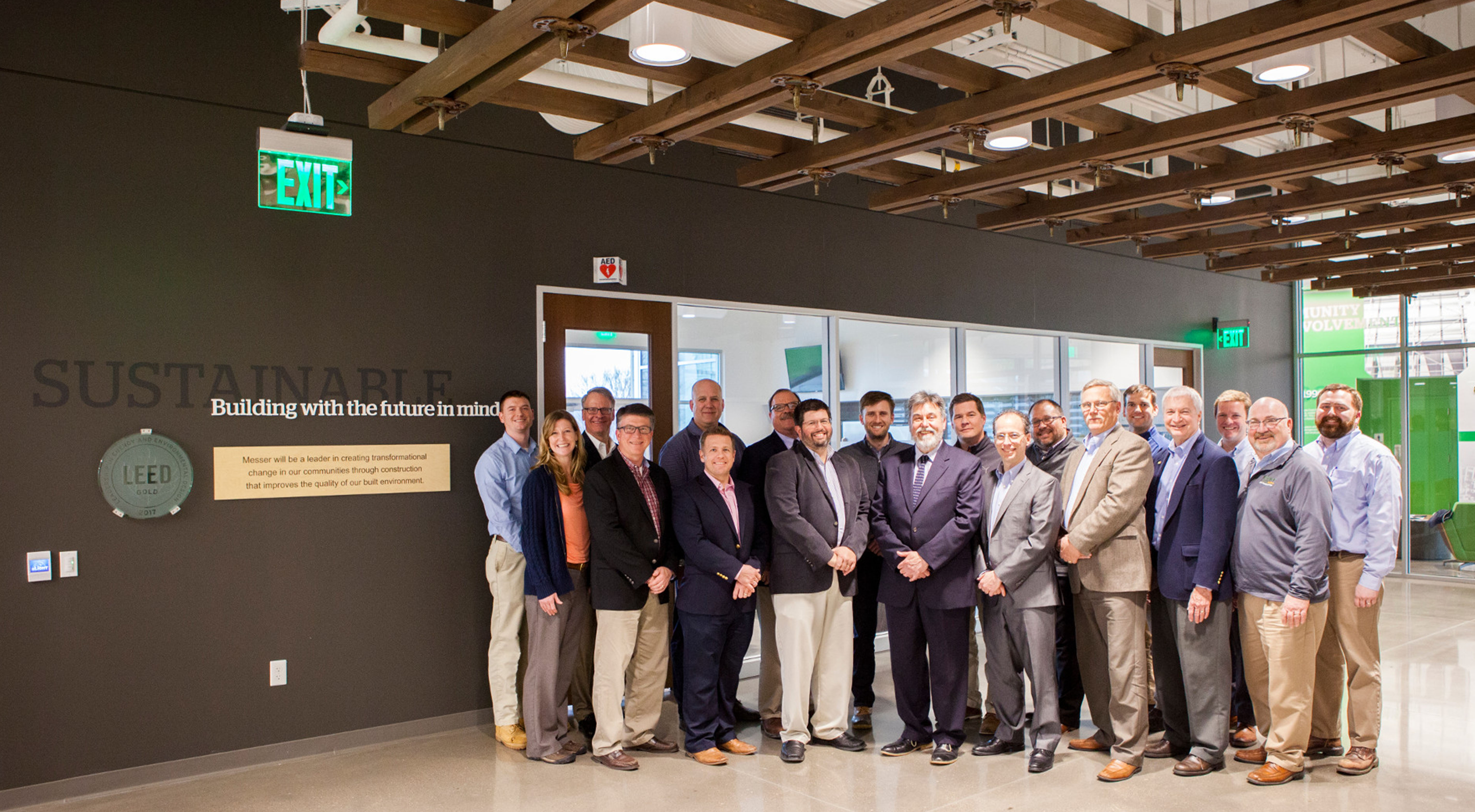 The project team stands beside signage talking about sustainability