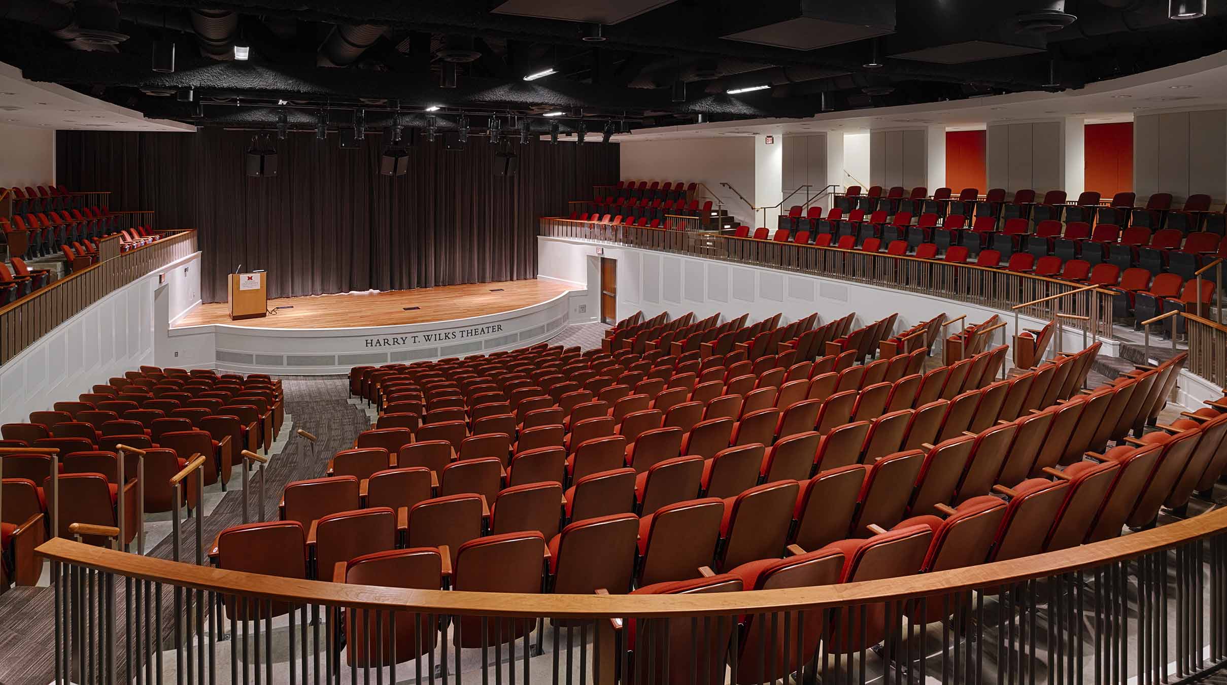 500-seat theater with red seats and a natural wood stage