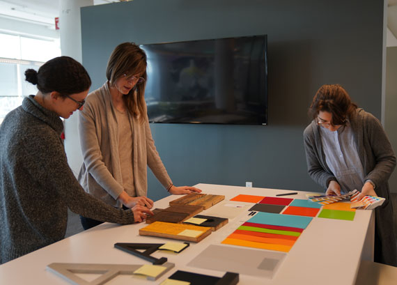 Three woman reviewing graphic design samples