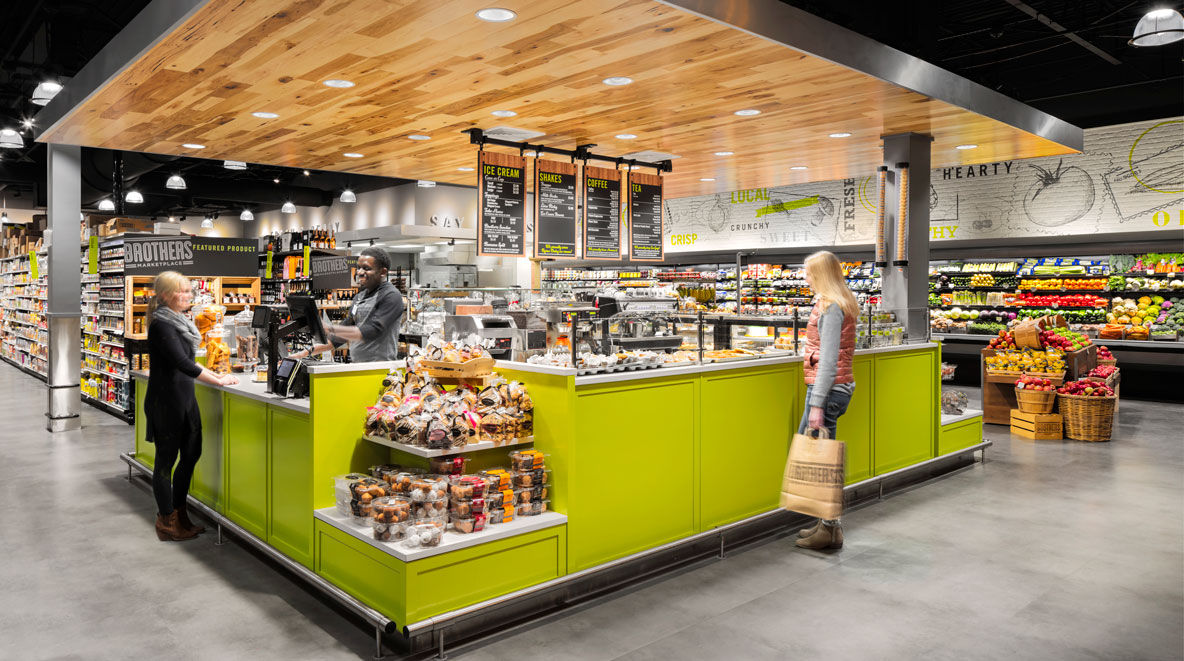 Two women stand by an ice cream counter and a man stands behind the counter at Brothers Marketplace