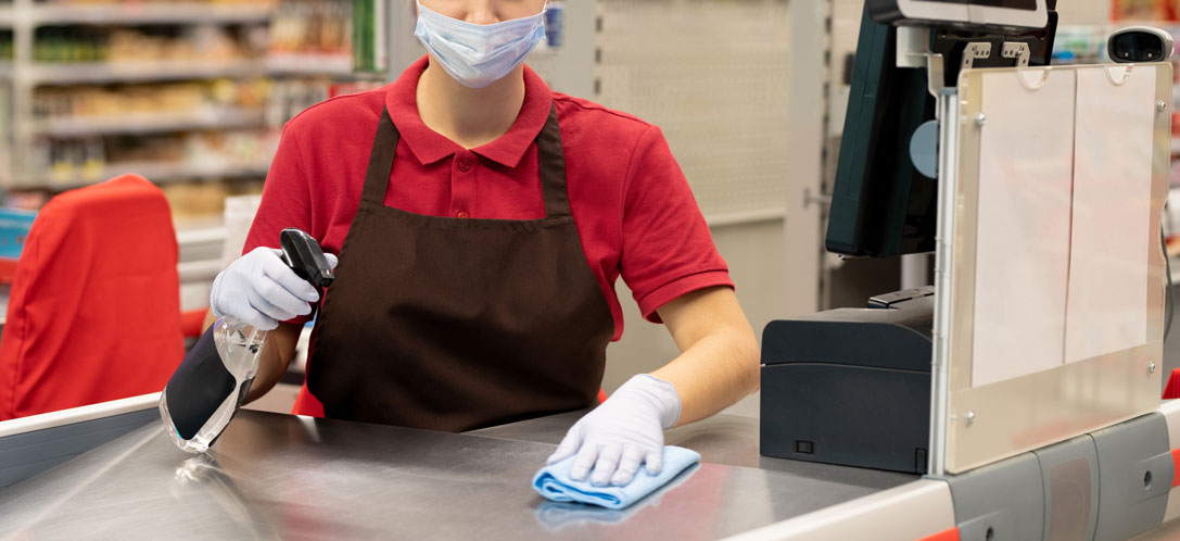 Retail worker sanitizing at registers
