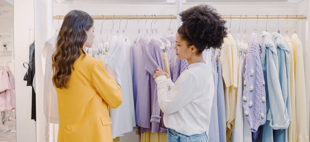 Two women shopping for clothes in a pastel-themed store