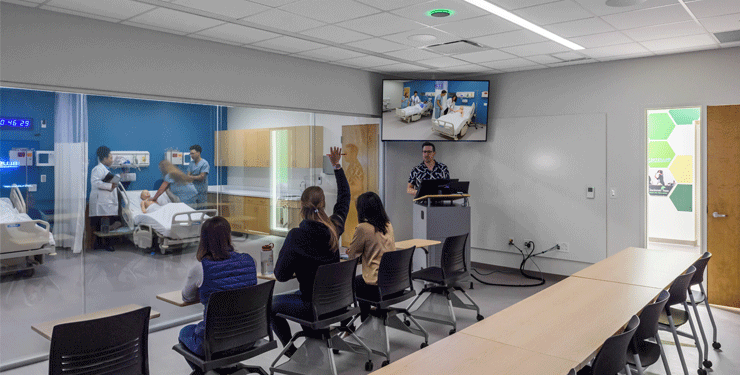 Students immersed in a nursing simulation environment, observing hands-on practice sessions where nurses refine their skills in a controlled setting.