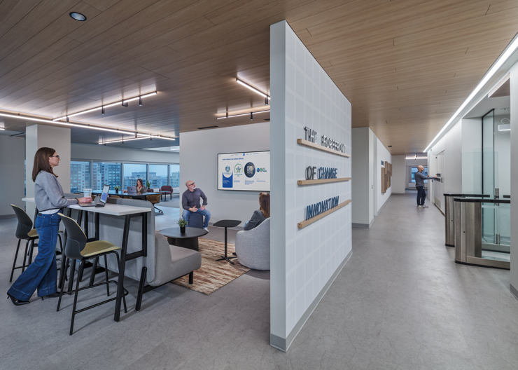 Employees collaborate together in semi-private area with couches and a tv monitor