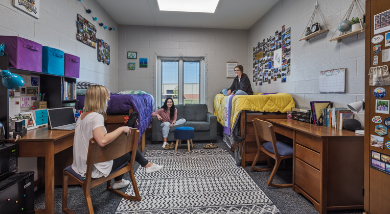 Three students hang out together in a residence hall room