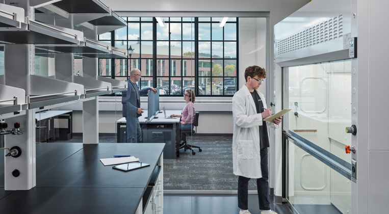 A researcher stands inside a lab with a transparent glass wall