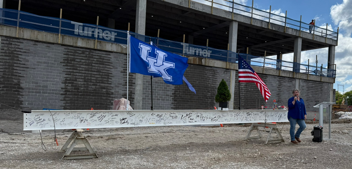 A large white beam with hand-written signatures is on display before a topping-out ceremony