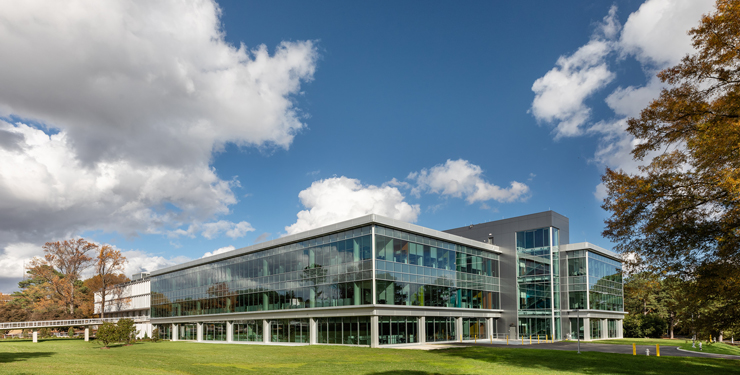 A building is shown with blue skies above it and prominent white clouds
