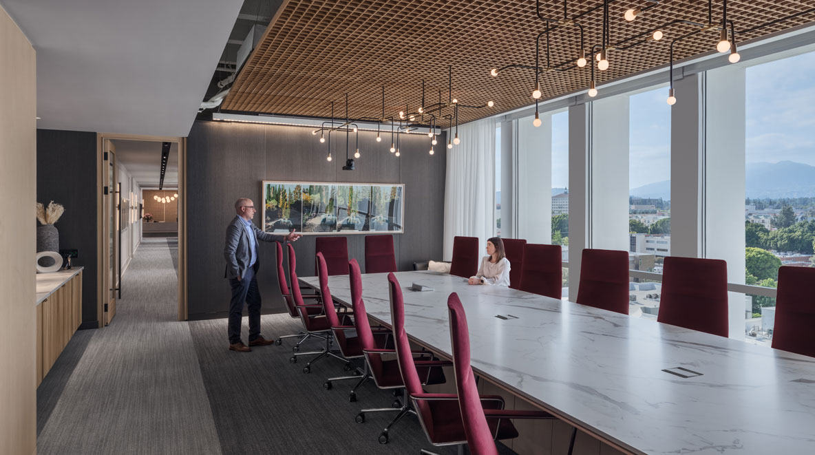 Two people in a board room with a mountain view.