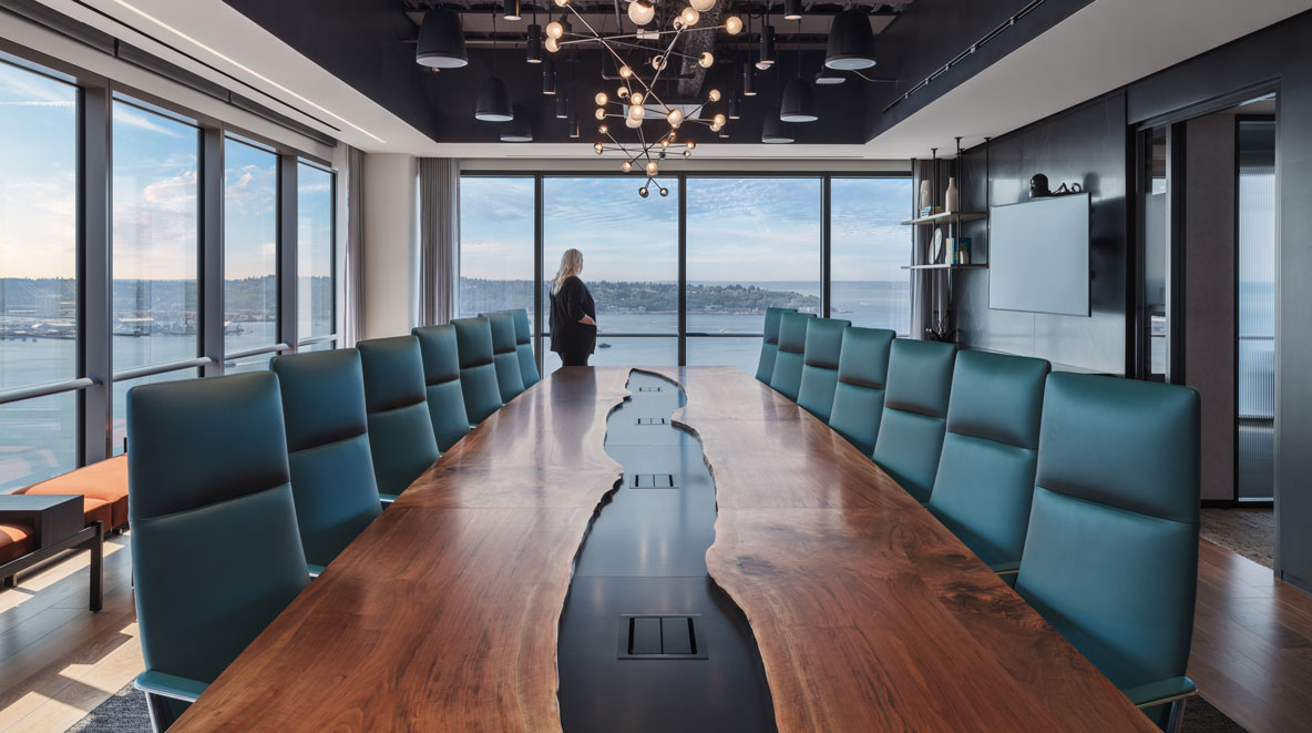 Women looking out of a glass window to water in a grand meeting room