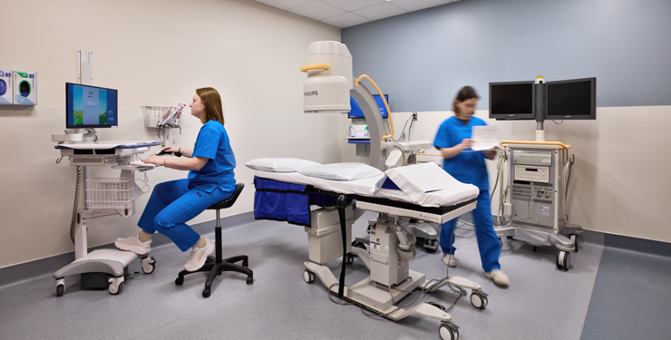 Two healthcare workers prepping a room for a patient.