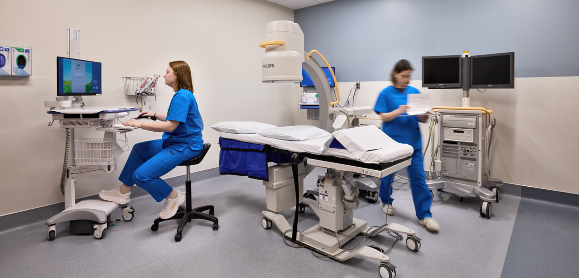 Two healthcare workers prepping a room for a patient.