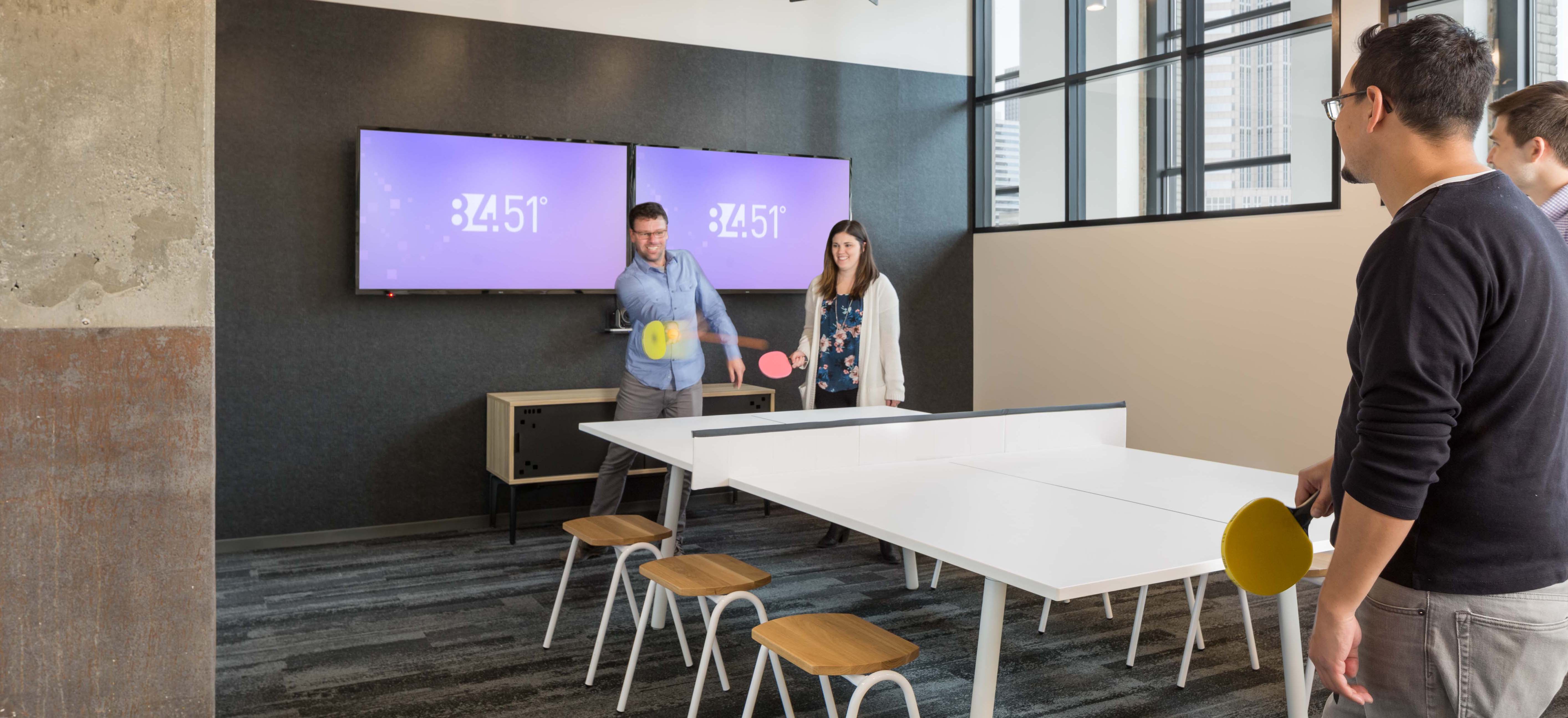 84.51 employees playing ping pong together