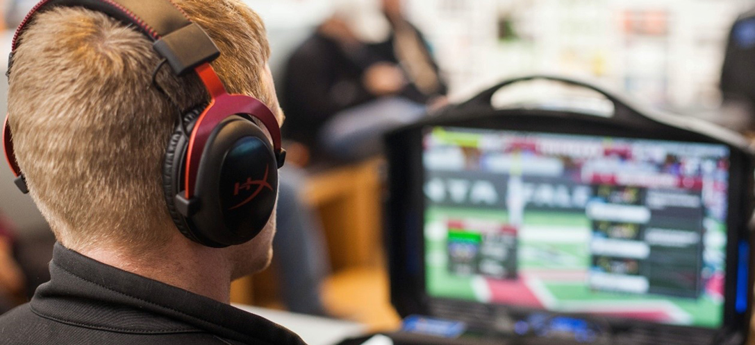 A student wearing headphones plays a game at his computer