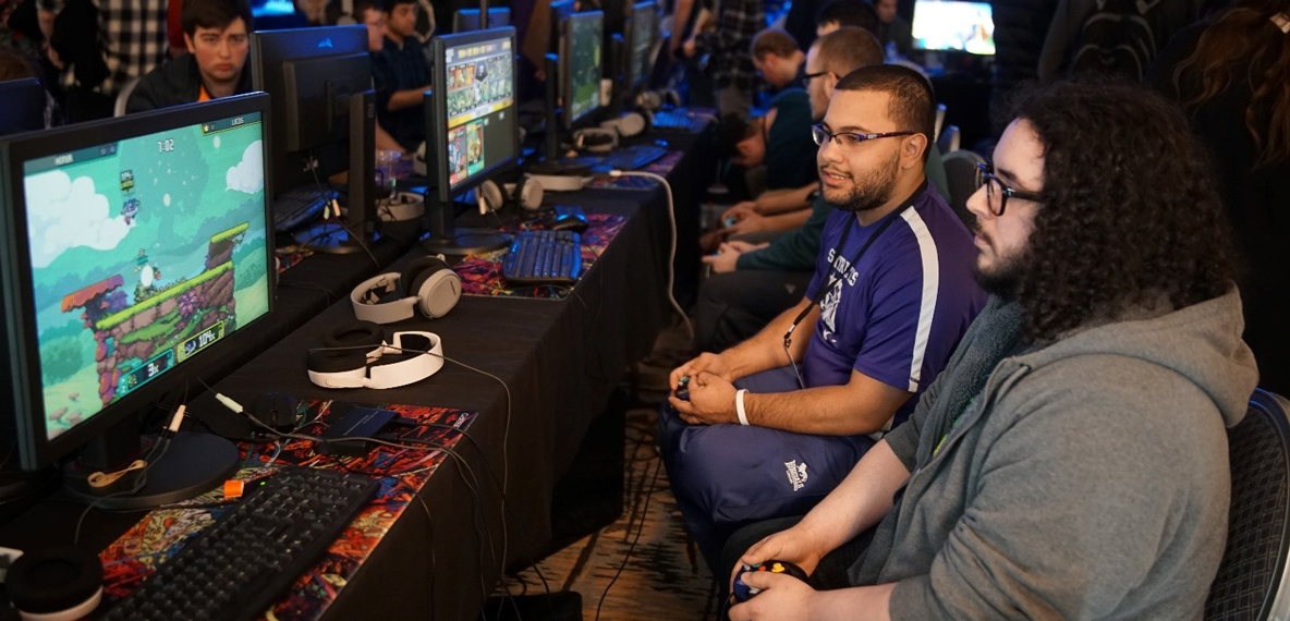 Two students play a game on a computer in front of them
