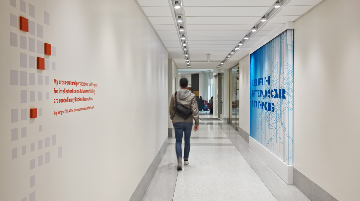 A hallway features a lenticular wall on the right and an inspirational alumni quote on the left