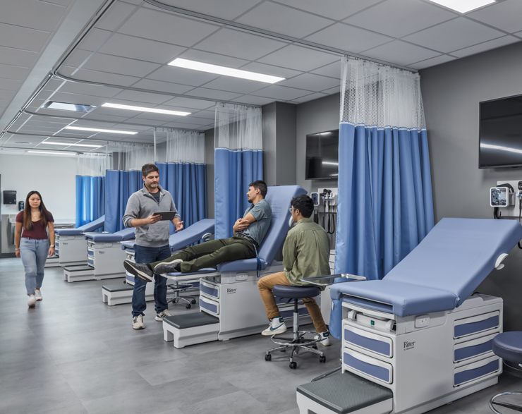 Students take a class in a new classroom with hospital beds