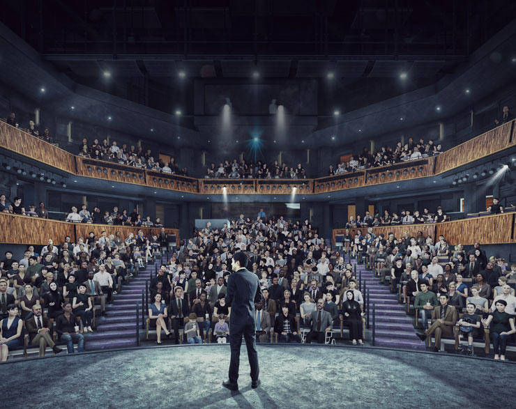 Patrons in the audience watch a presenter on stage