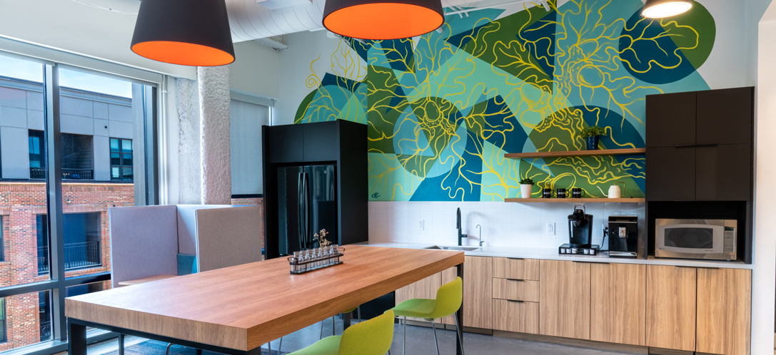 A green and blue mural is the background in an office kitchen
