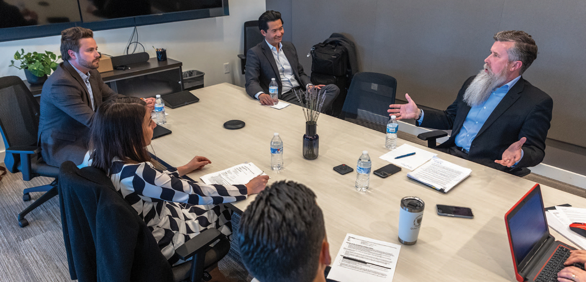 A group of panelists have a conversation together while sitting at a table.