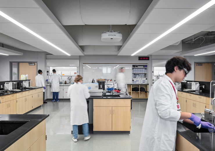 Chemistry students gather around work areas while performing labs