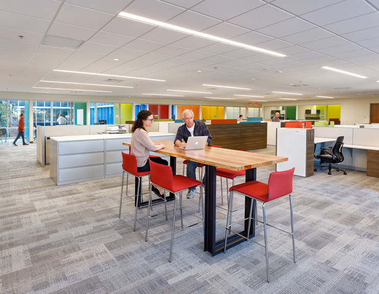 Employees gather at a large table in the center of the open office