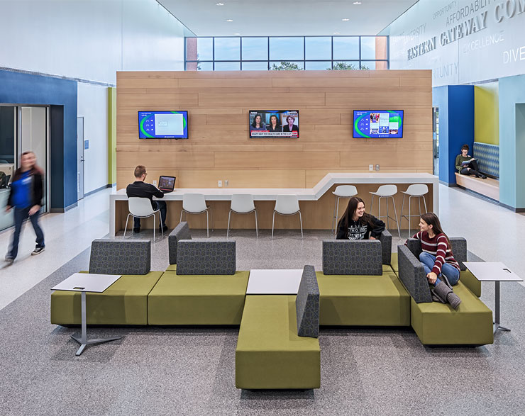 Two students sit on a large green couch in the common area