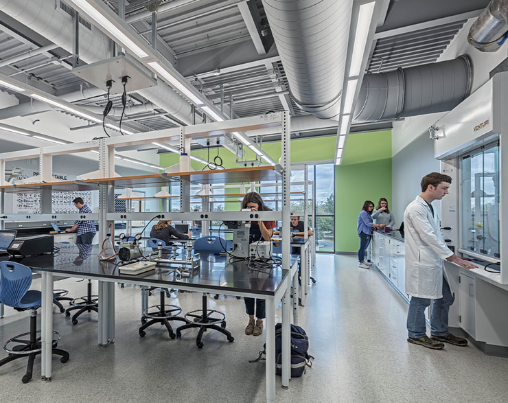 Students gather at a central table in the middle of a lab