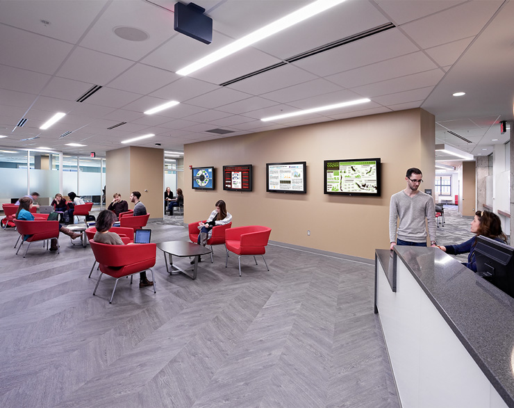 Students sit with others in a large open space next to the reception desk