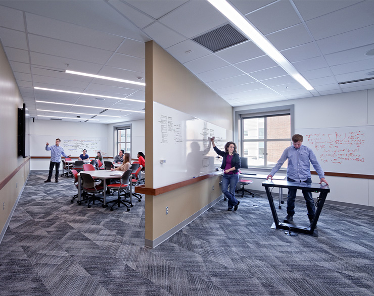 A large room is split with a wall containing white boards