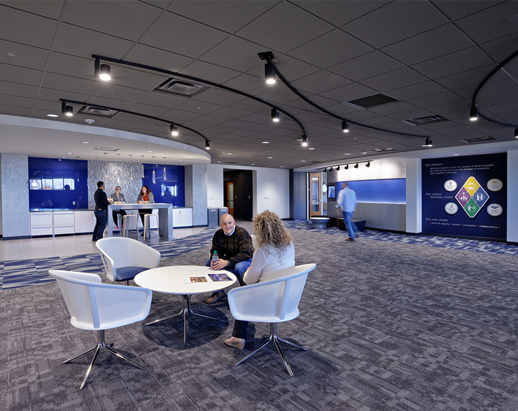 Two employees sit around a small table in the open collaboration area