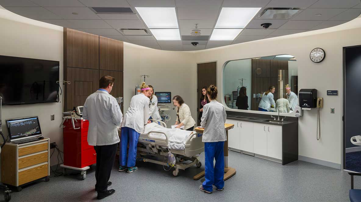 Students gather around a hospital bed