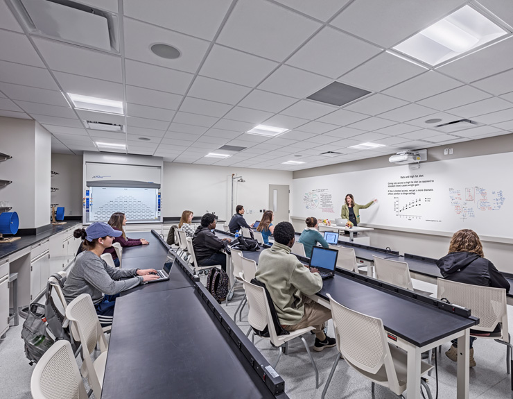 In a classroom, students look toward the front of the class at their teacher