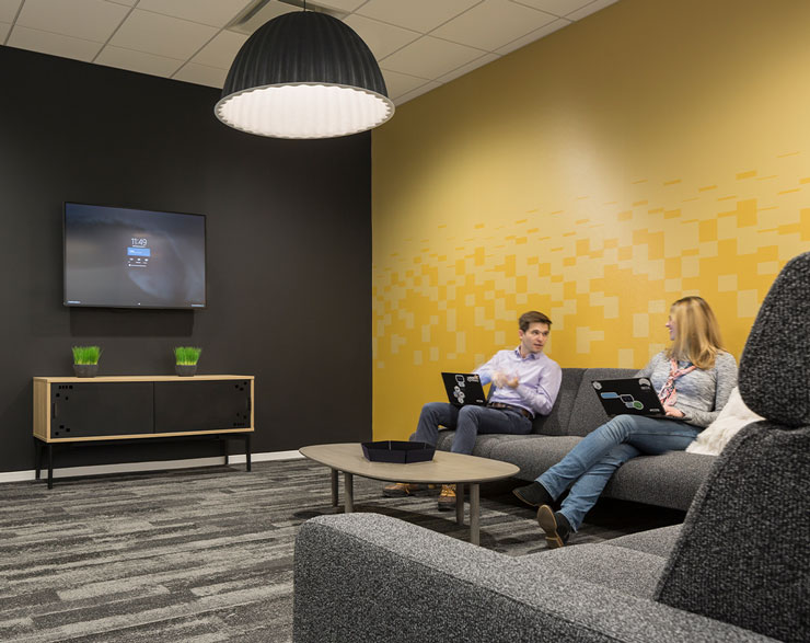 Employees talk in a huddle room