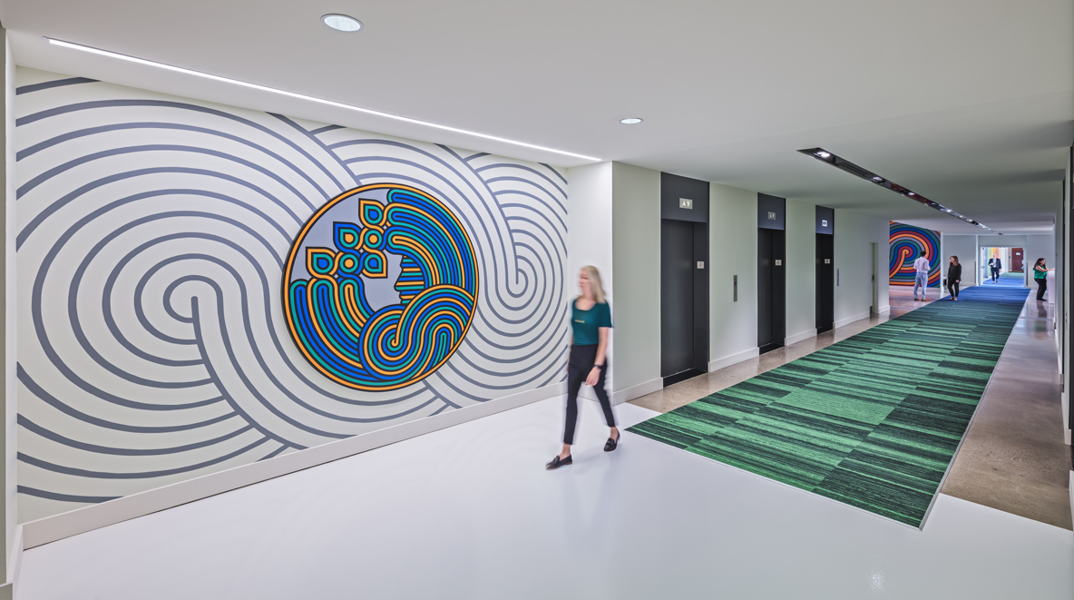 A P&G employee walks past a green and blue piece of art on the wall