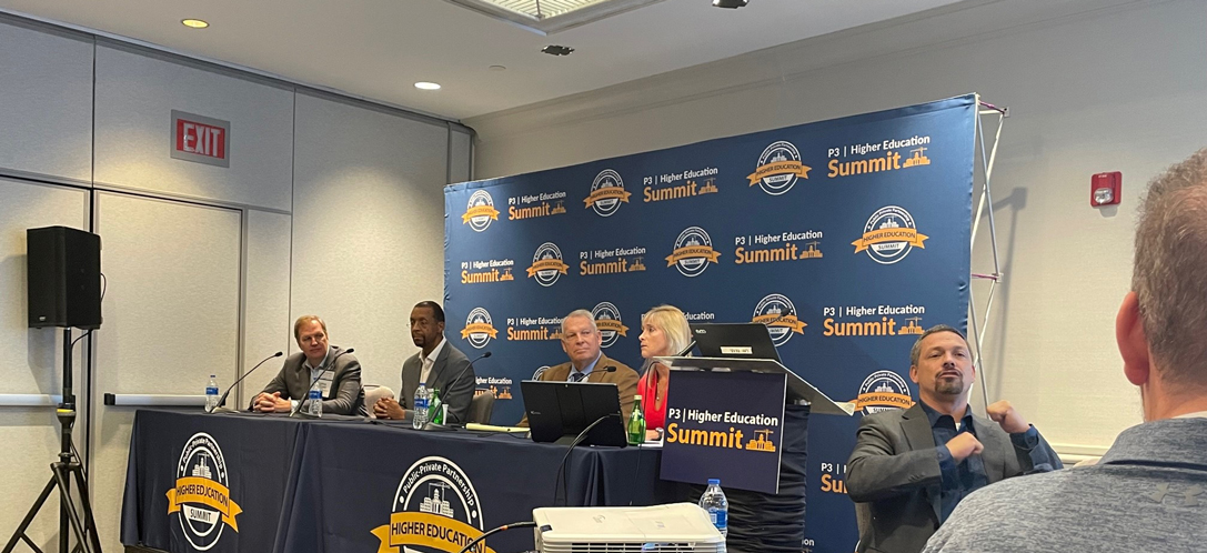 Panelists sit together at a table and gather for a discussion 