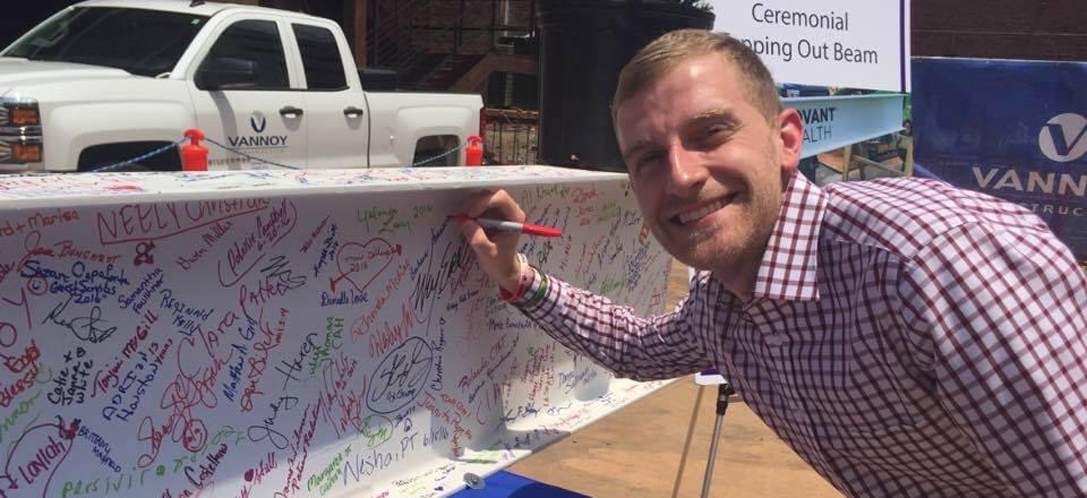 Bryan Ruby signs a white beam that is covered in colorful signatures