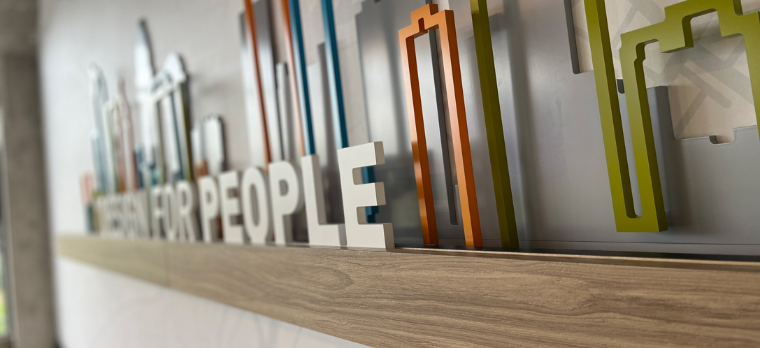 A close-up shot of "Design for People" letters backed by colorful silhouettes of buildings