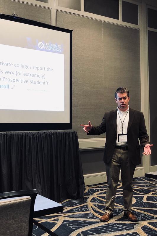 Michael Garvey standing in front of a screen with his presentation