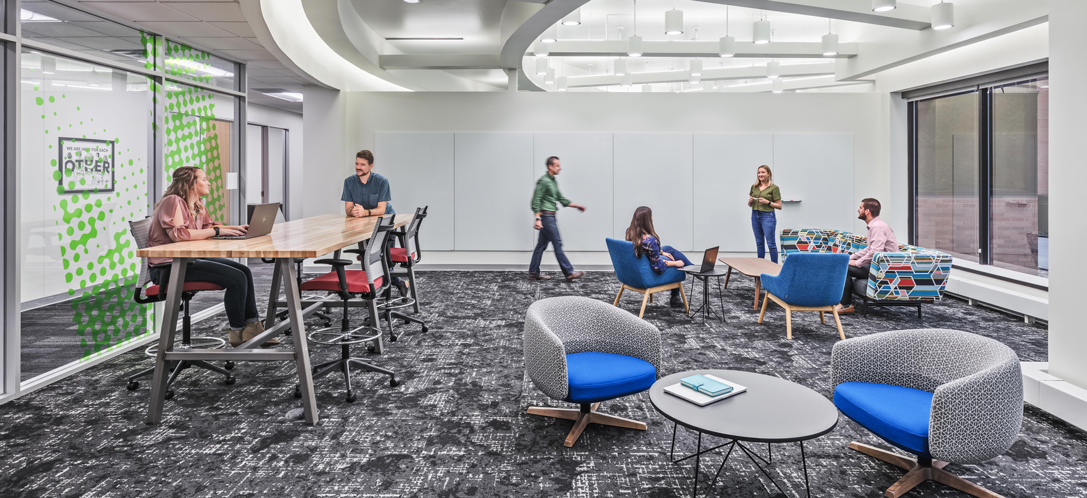 Two groups of employees collaborate together in a medium-sized space