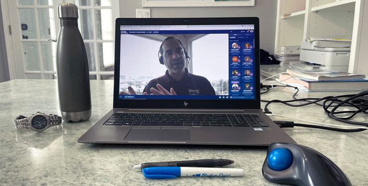 A computer is set up on a desk and on the screen a person is presenting