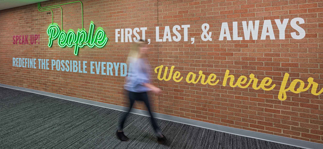 Image of person walking by a wall display of motivational sentence.