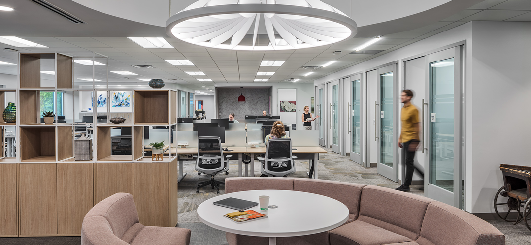 image of office space with couch seating, individual rooms, and tables with desks
