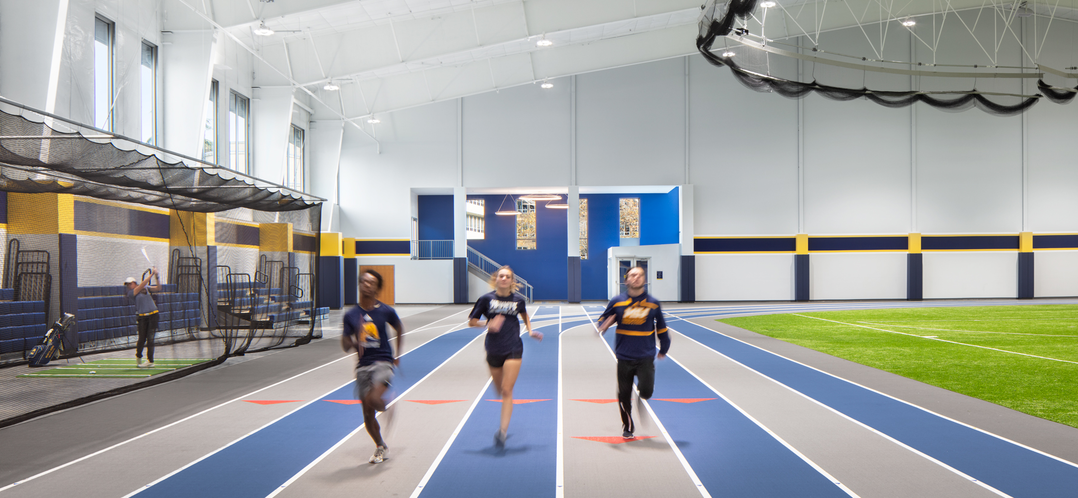 image of the interior of a recreation center with three people running on a track