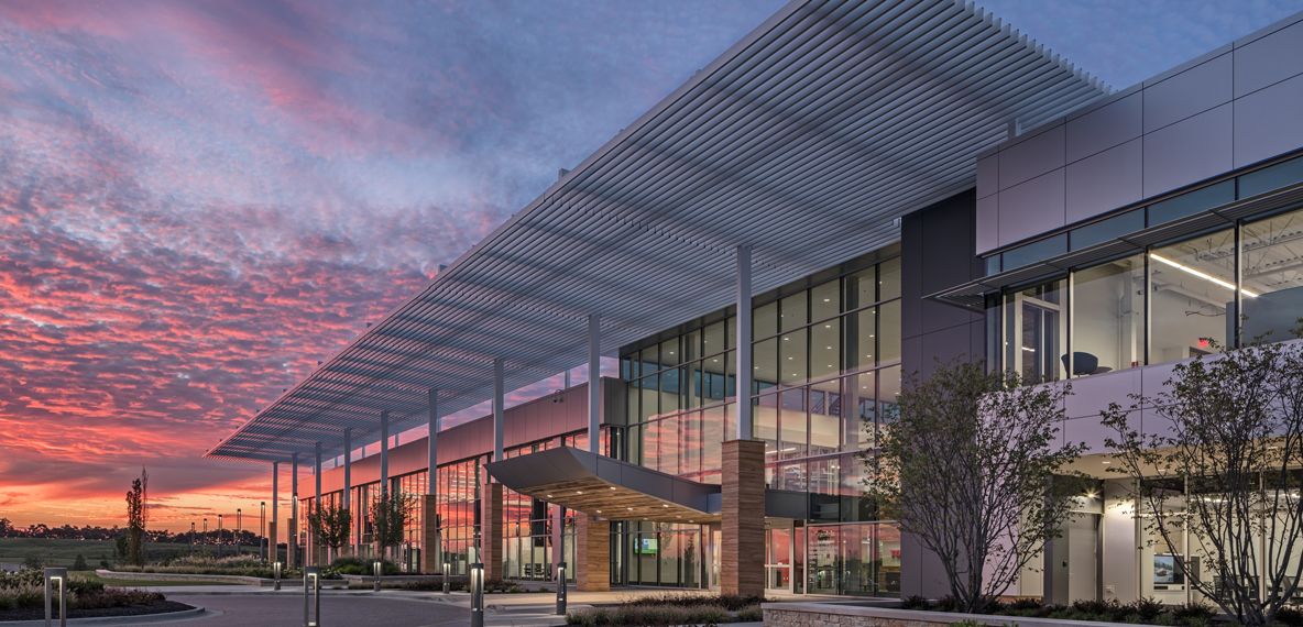 A red and pink sunset is shown in the background of a prominent building