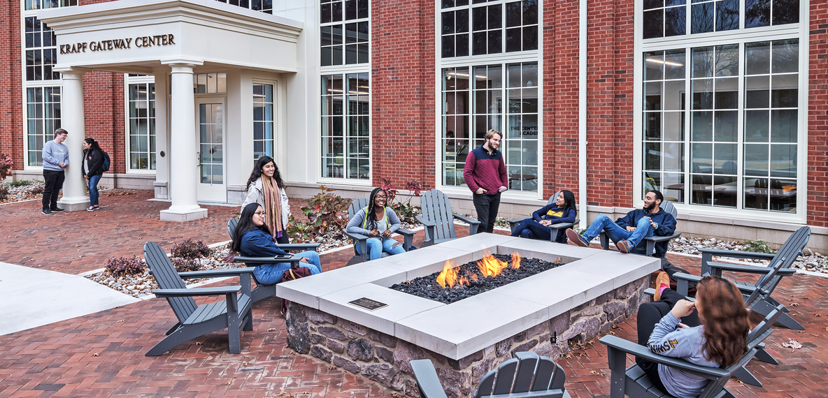 Image of students at a firepit outside of a college building